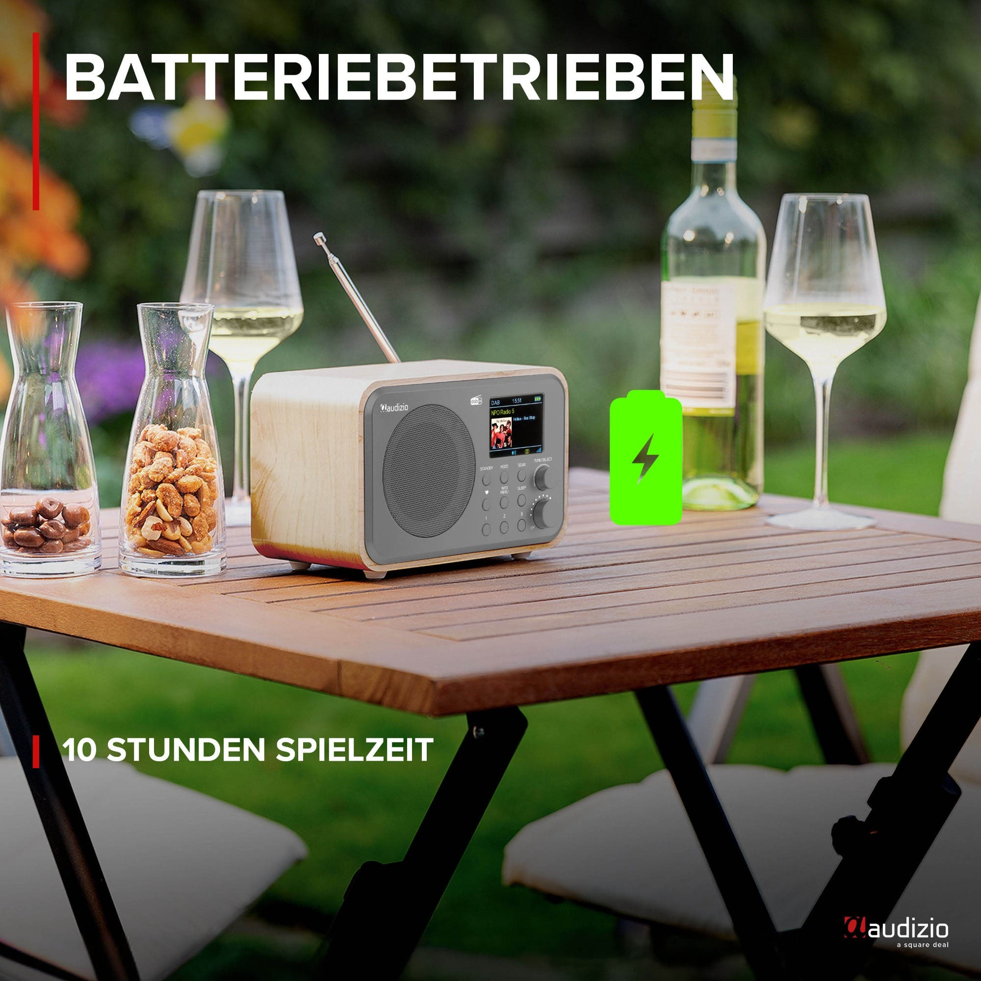 Una radio de madera en una mesa exterior con vino y aperitivos. Funciona con pilas.