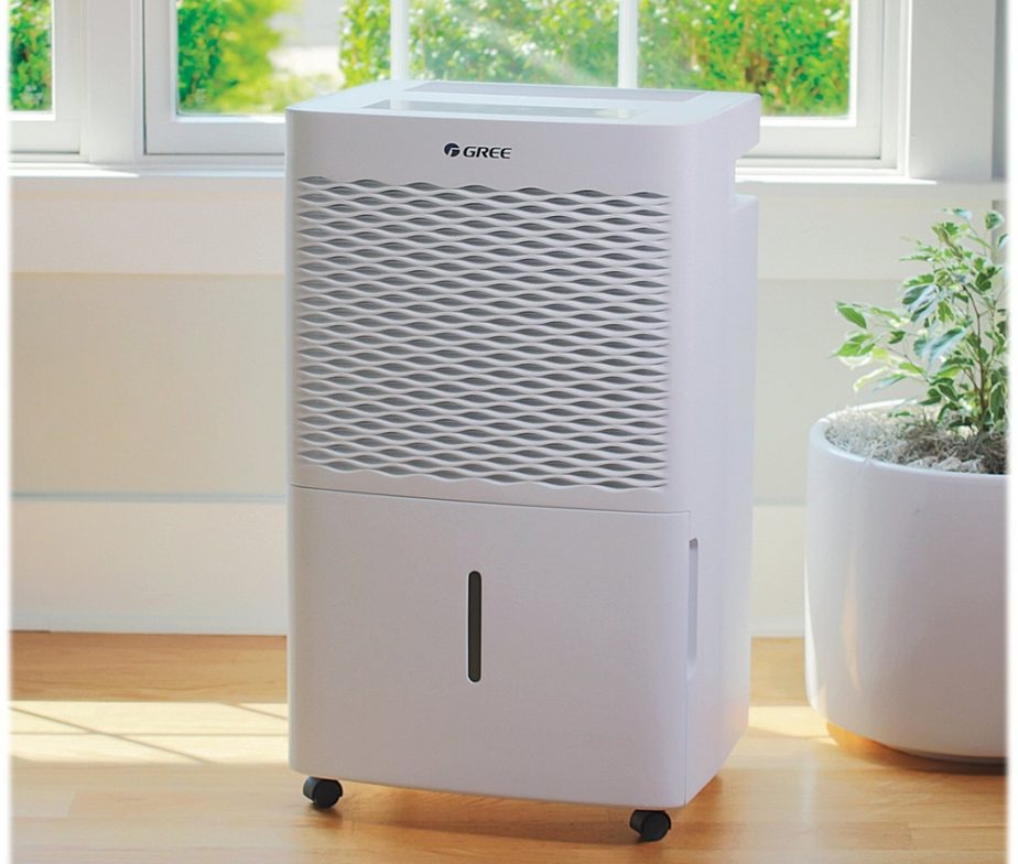 A white Gree dehumidifier with a water level indicator sits on a wooden floor.