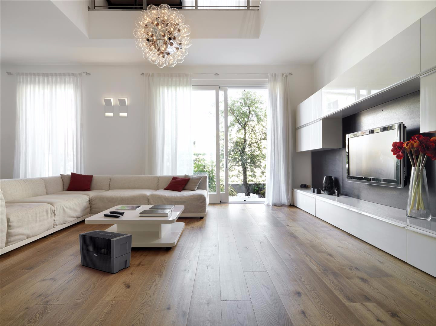 Modern living room with large sofa, coffee table, TV, and glass door to outdoors.