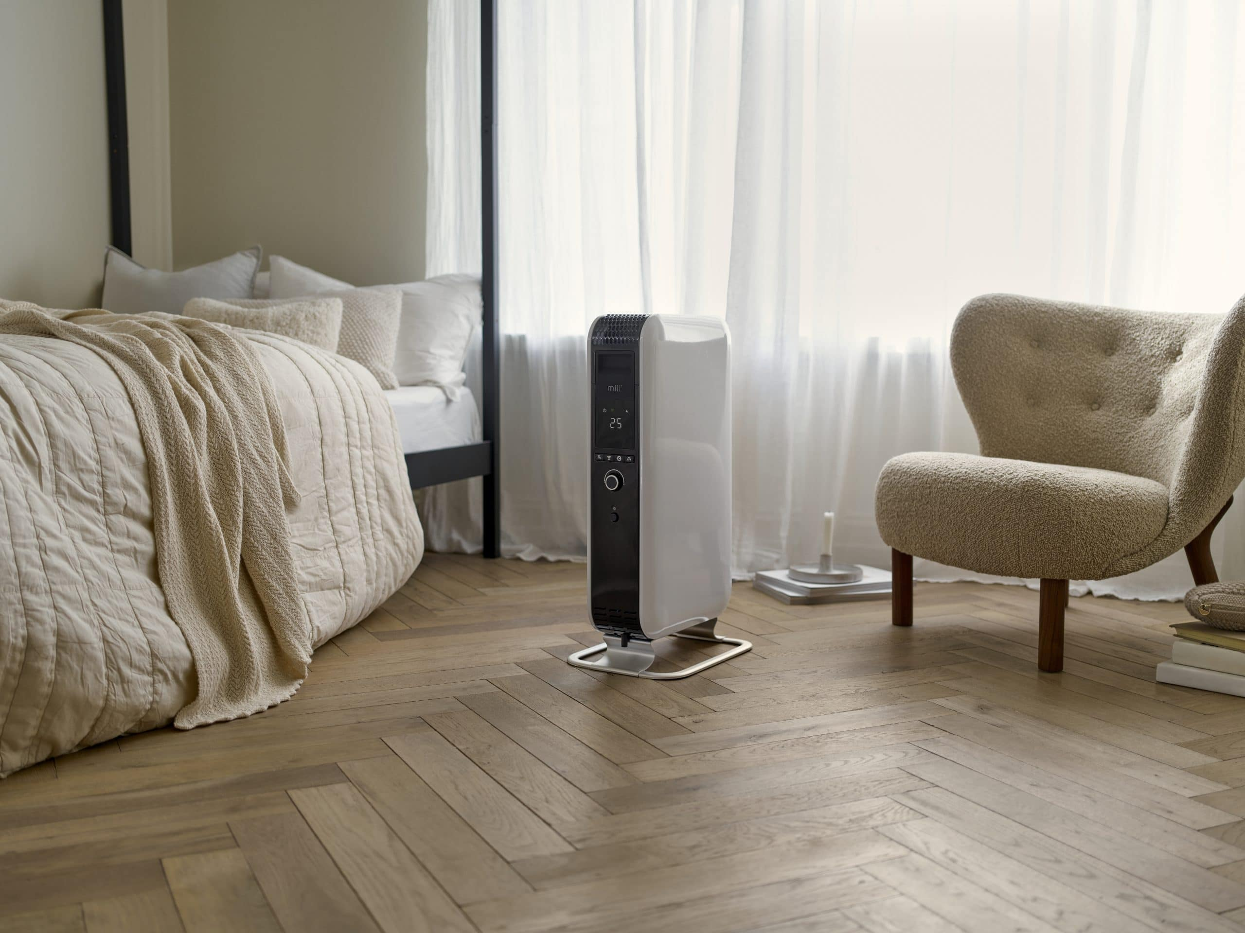 Un radiador blanco junto a una cama y un sillón.