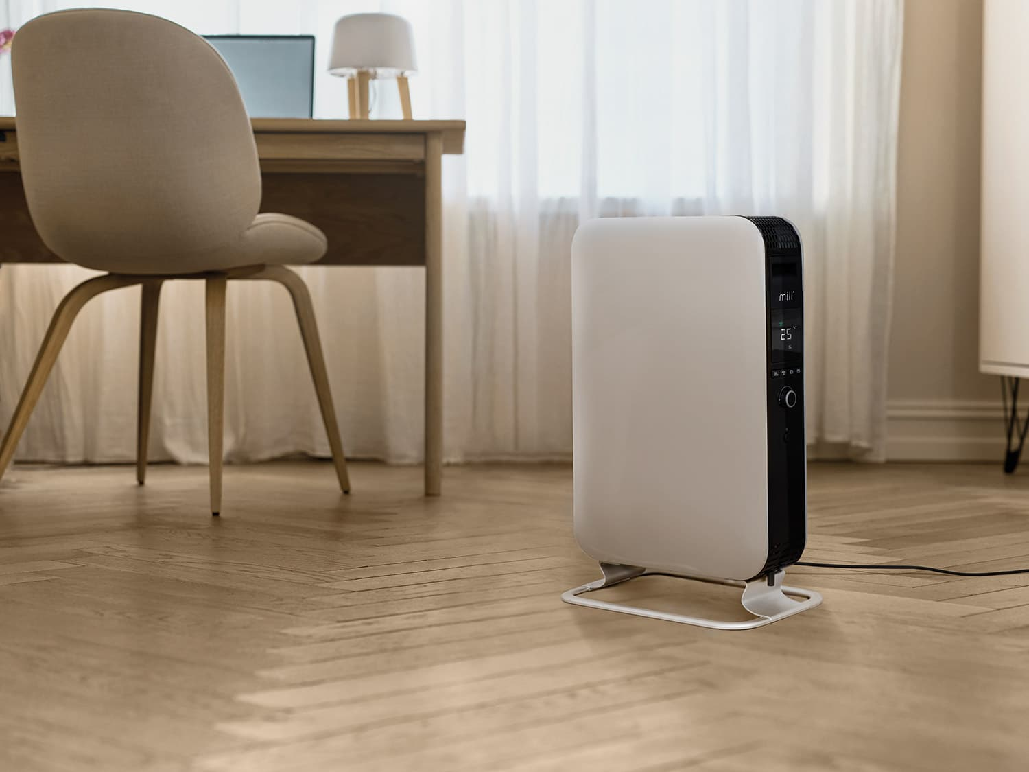 Un radiador blanco está sobre un suelo de madera junto a un escritorio con silla.