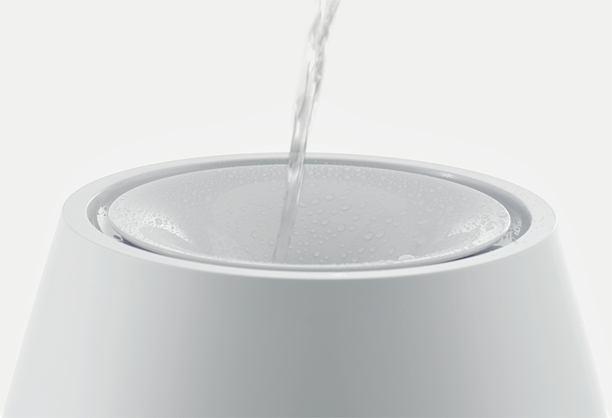 Water flows into a white bowl covered with droplets.