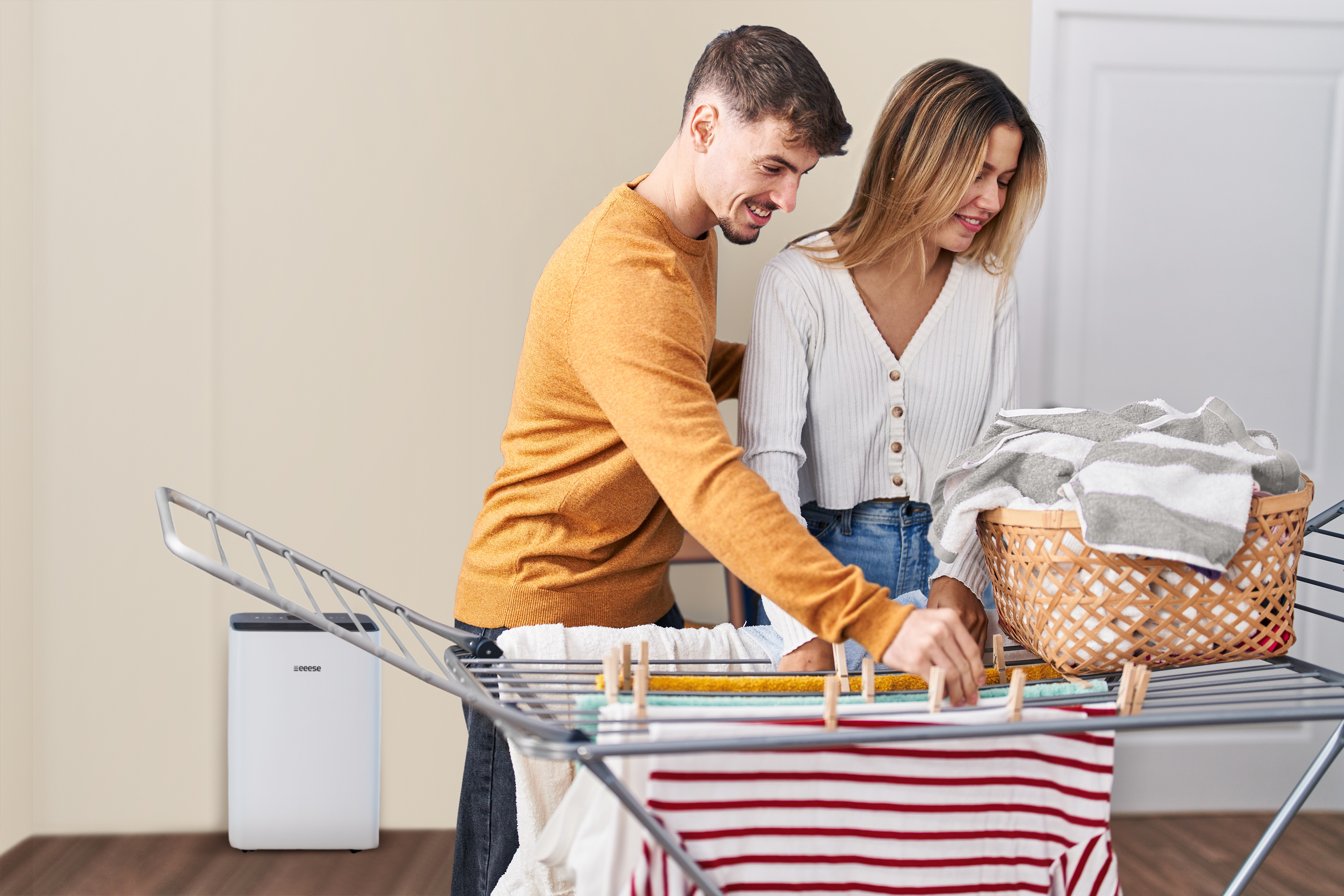 A man and a woman are hanging laundry on a drying rack.