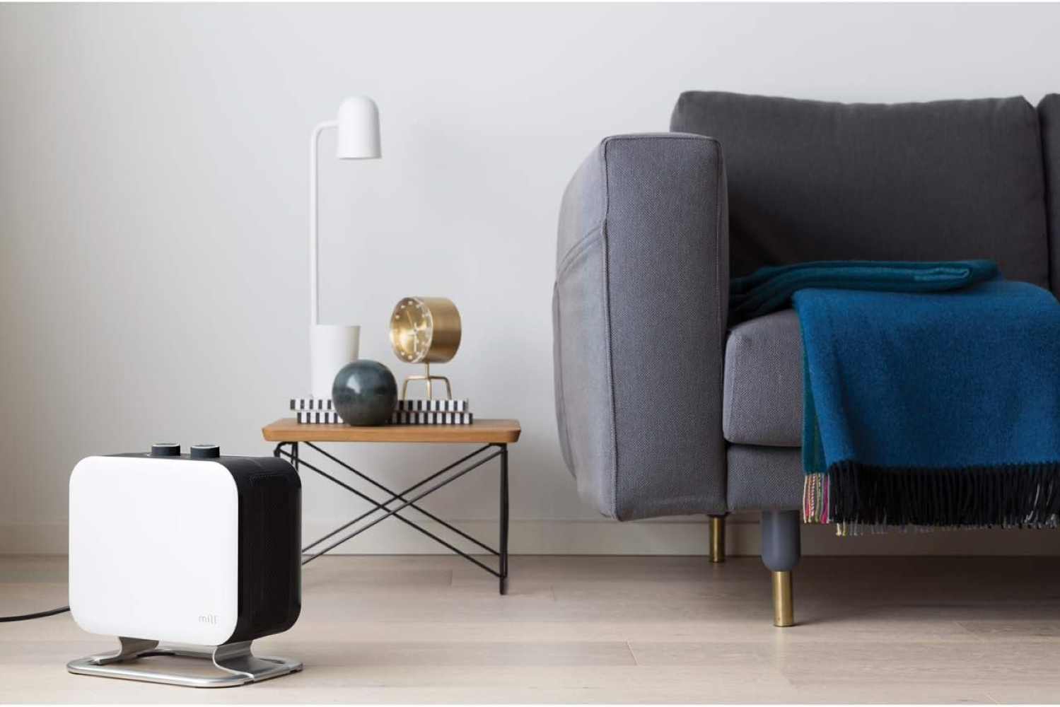 Un calefactor moderno junto a una mesita auxiliar con objetos decorativos y un sofá.