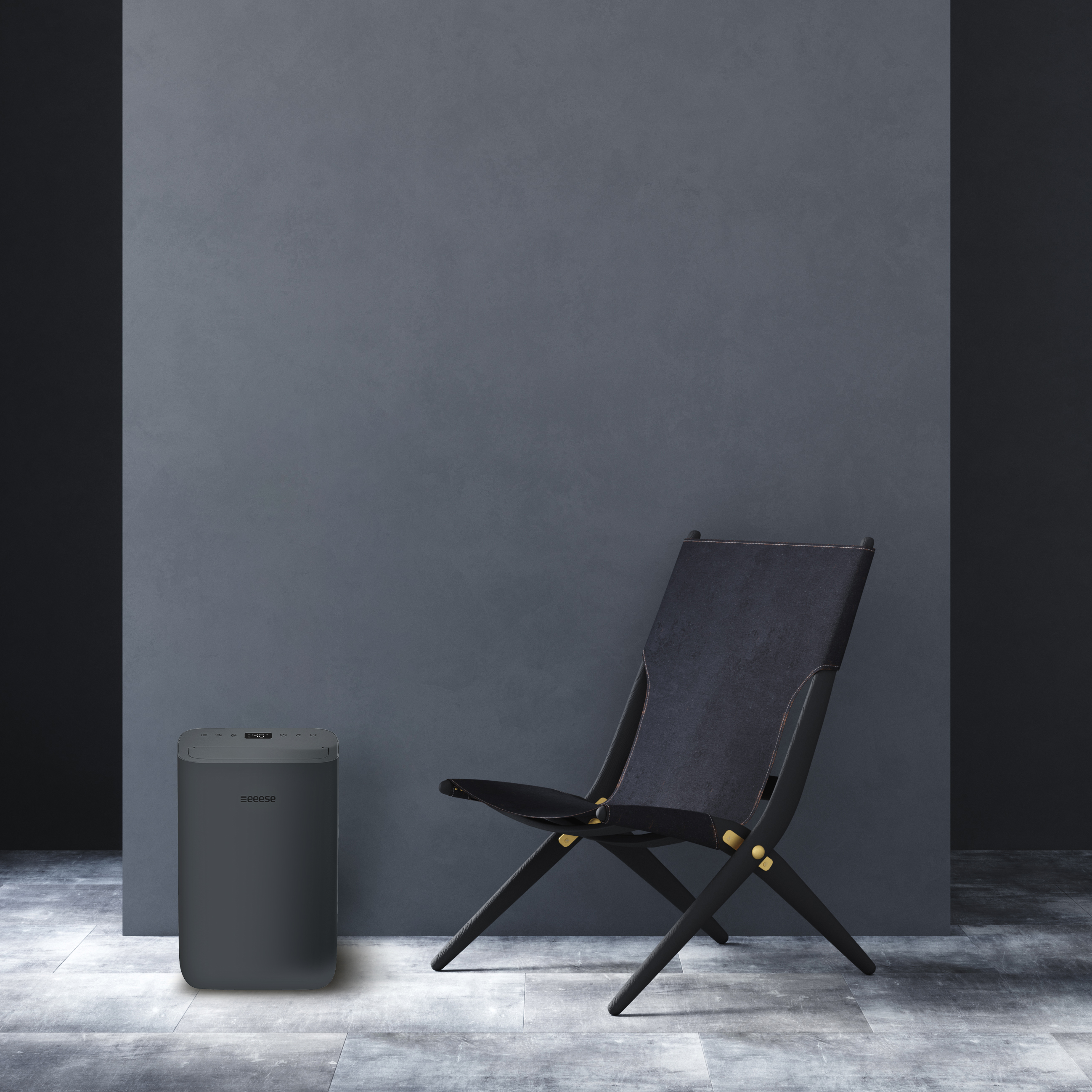 A dark chair and a grey device stand on a grey floor against a grey wall.
