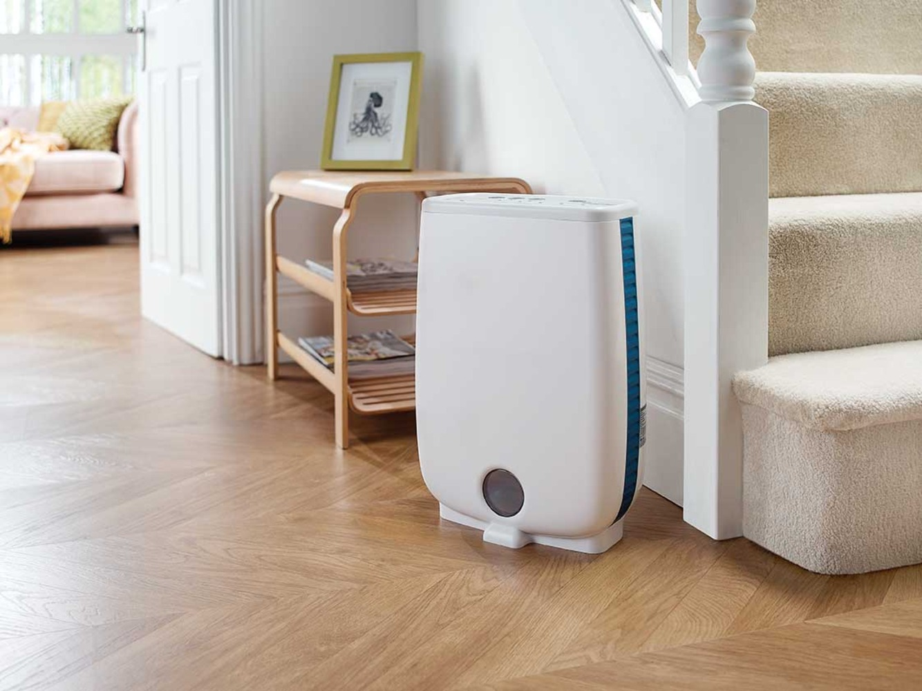 A white dehumidifier sits next to stairs and a small wooden table.