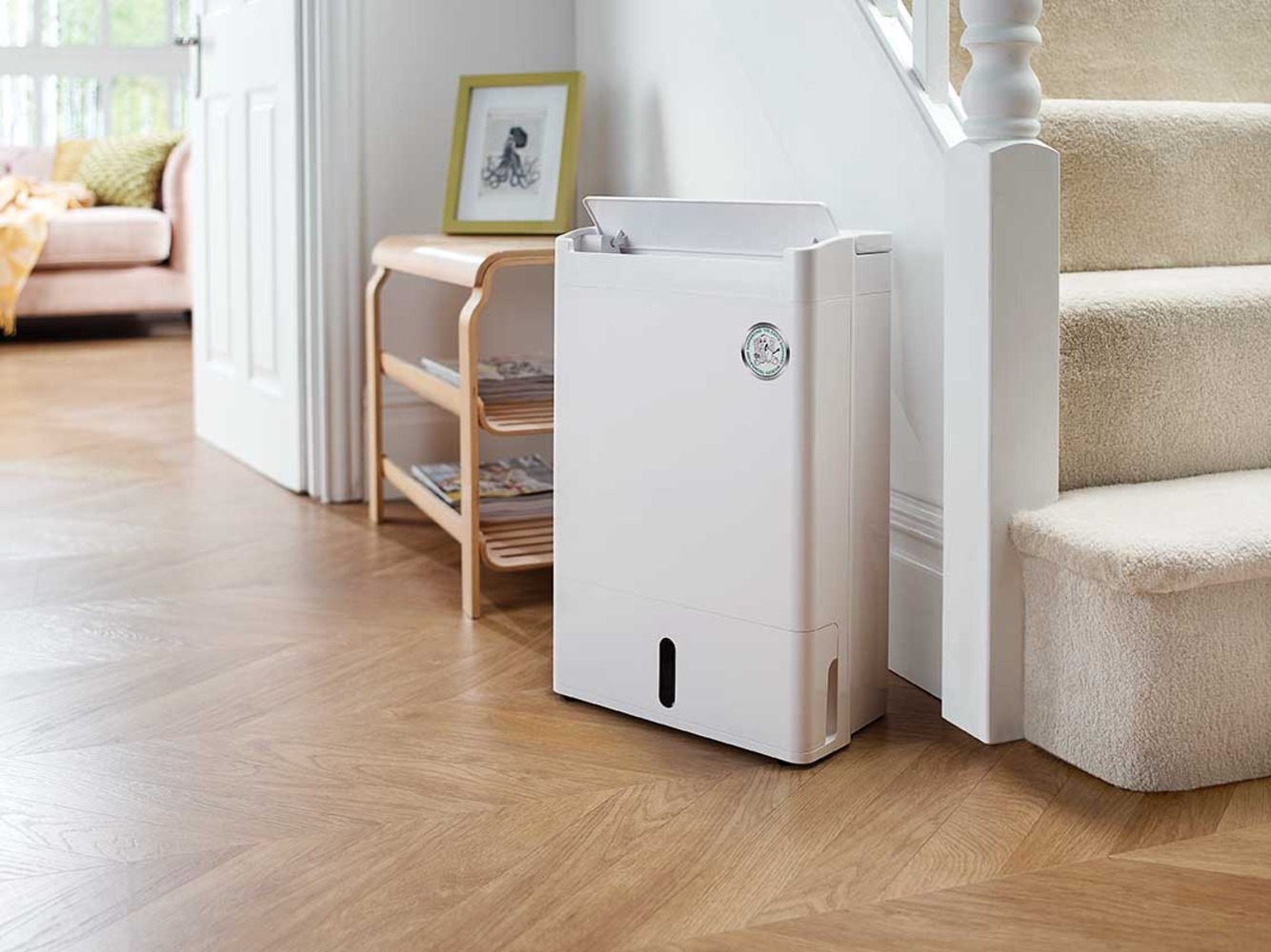 A white dehumidifier sits next to a carpeted staircase.