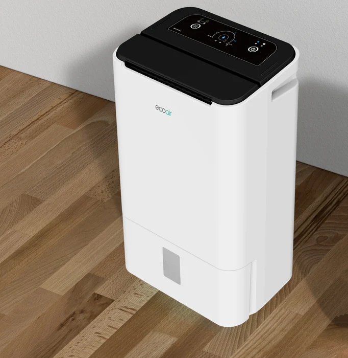 A white dehumidifier with a black top sits on a wooden floor.