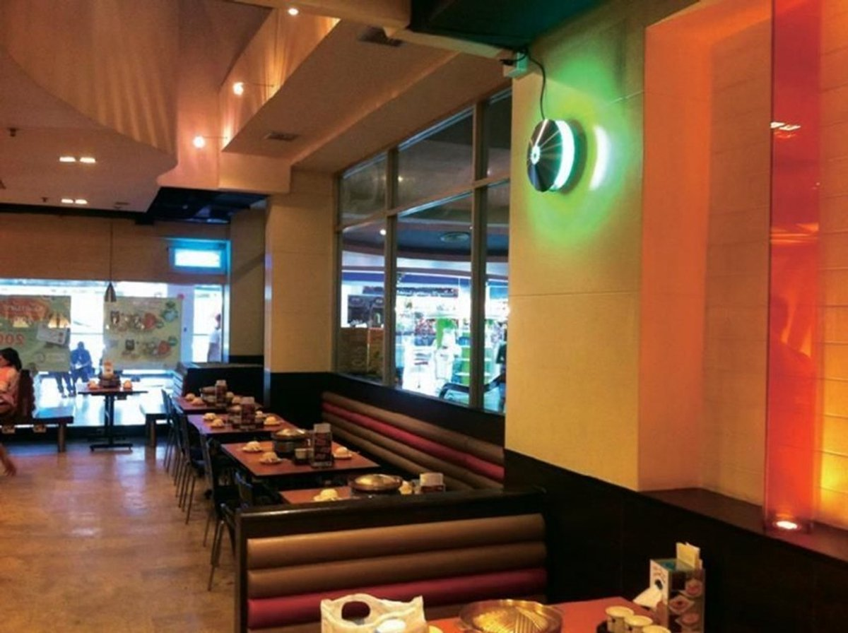 Interior of a restaurant with tables, booths, and a green light effect.