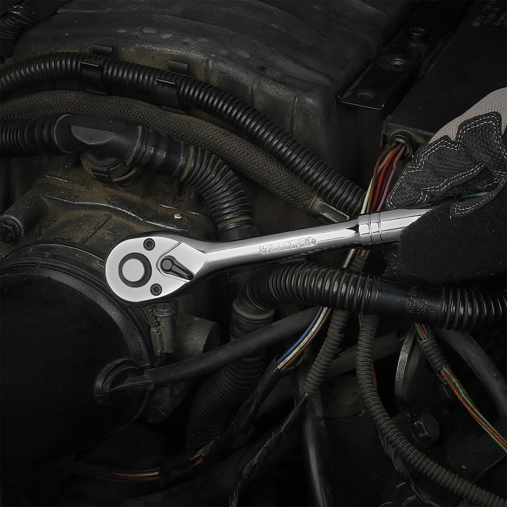 Eldivenli bir el, otomobil motor bileşenleri ve kabloları yakınında gümüş bir lokma anahtar tutuyor.
