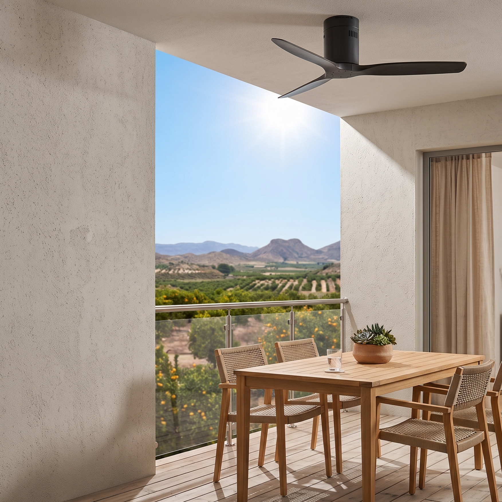Una mesa de madera con sillas en un balcón con vistas a huertos y montañas.