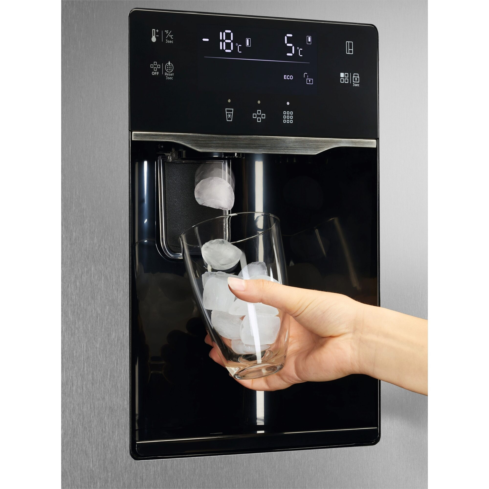 Una mano sostiene un vaso bajo un dispensador de hielo mientras caen cubitos de hielo.