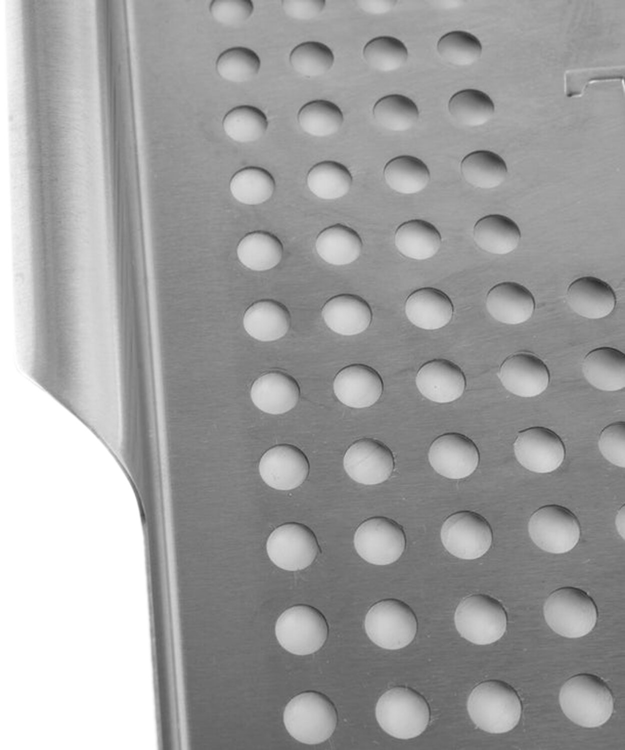 Primer plano de una superficie metálica con un patrón de agujeros circulares.
