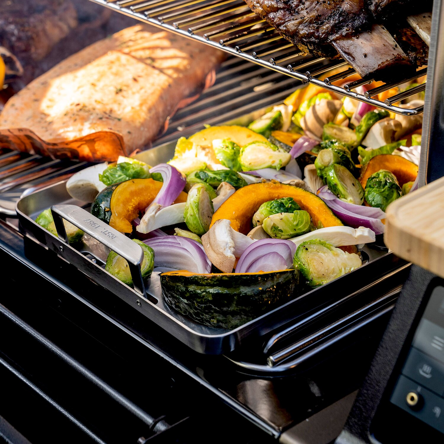 Una bandeja de verduras coloridas y carne cocinándose en una parrilla.