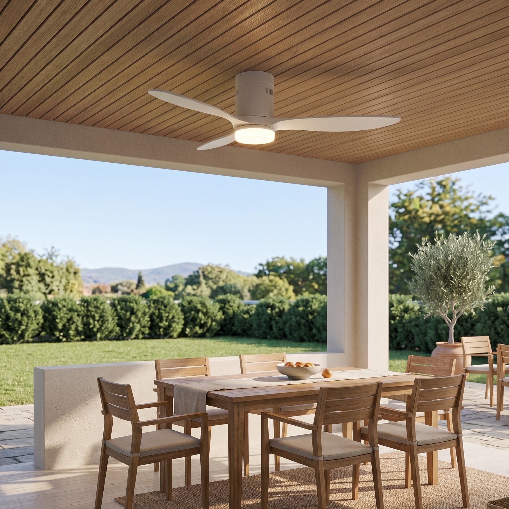 Un patio cubierto con mesa de comedor, sillas y ventilador de techo. Hay un jardín afuera.
