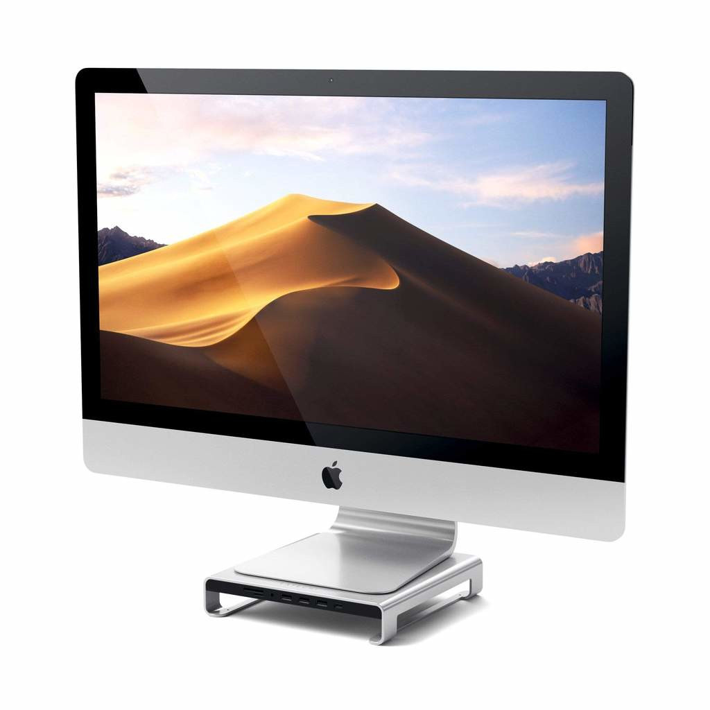 Un iMac argentato con sfondo di dune di sabbia su un supporto con porte.