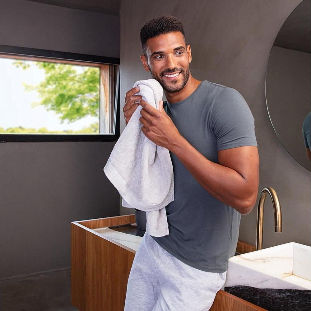 Ein Mann trocknet sein Gesicht mit einem Handtuch im Badezimmer.