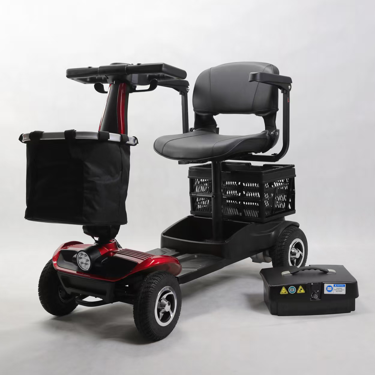 Un scooter elettrico rosso e nero con sedile, cestini e pacco batteria separato.