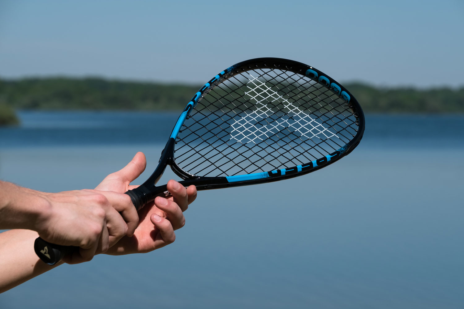 Persona che tiene una racchetta nera con accenti blu su un lago.