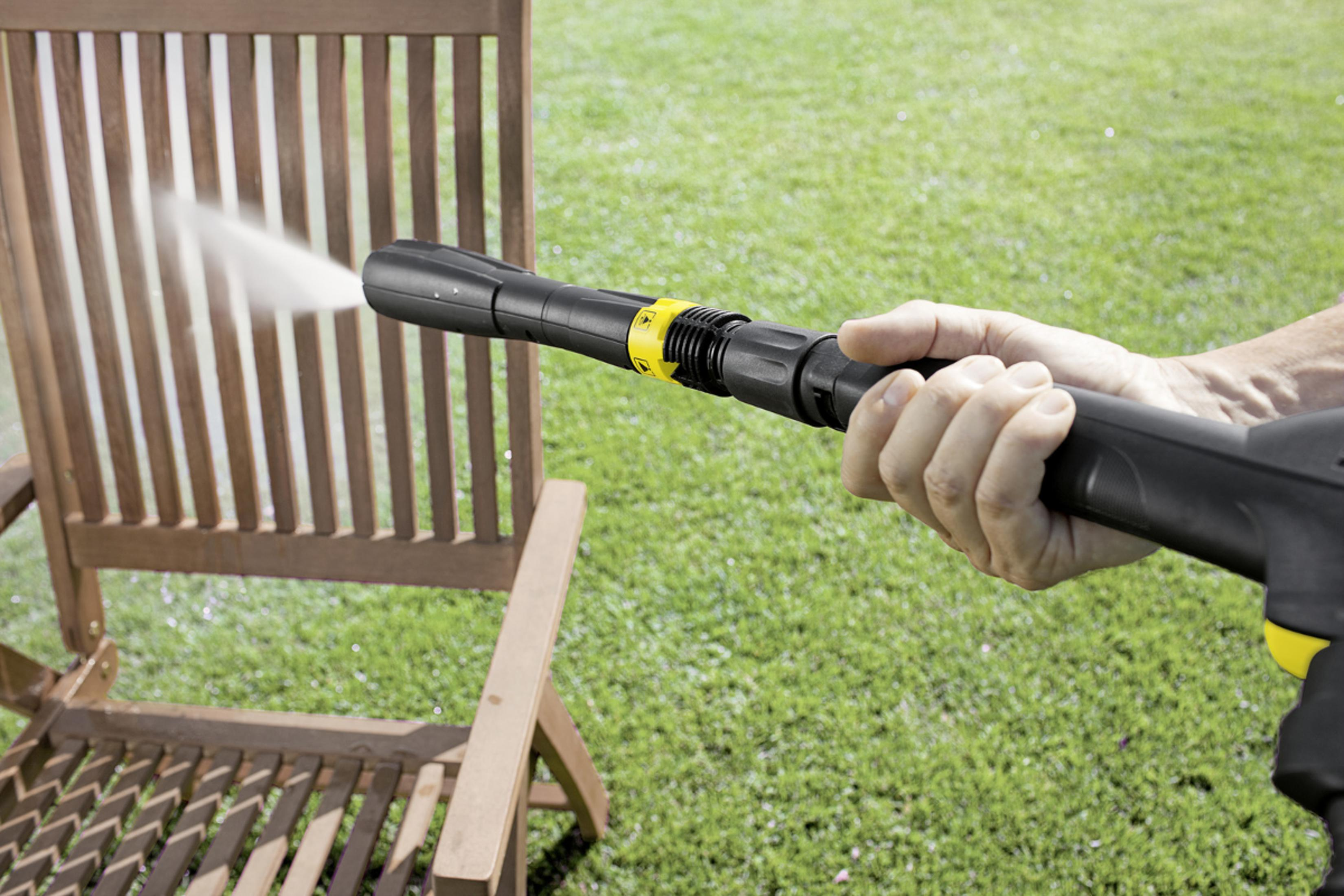 Un'idropulitrice spruzza acqua su una sedia di legno sull'erba.