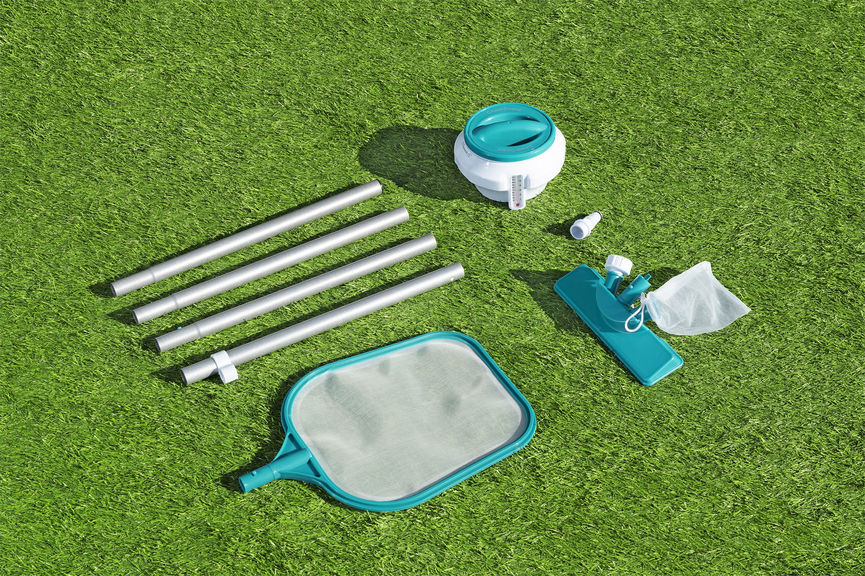 Articoli per la manutenzione della piscina su erba sintetica: aste, retino, termometro e dispenser.