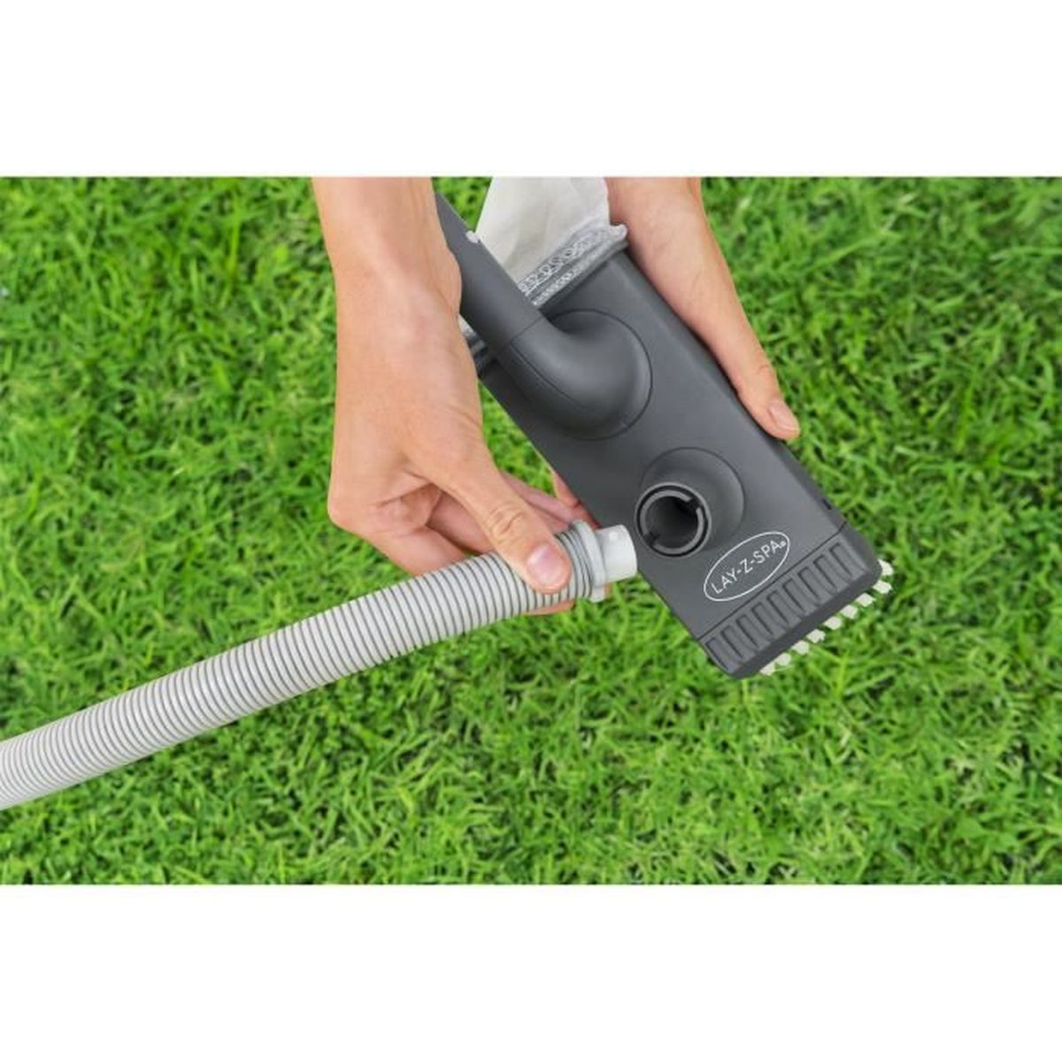 Mani che collegano un tubo grigio a un aspiratore Lay-Z-Spa sull'erba.