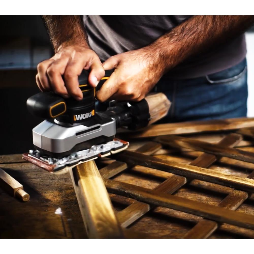 Uomo leviga grata di legno con levigatrice elettrica. Primo piano su mani e attrezzo.