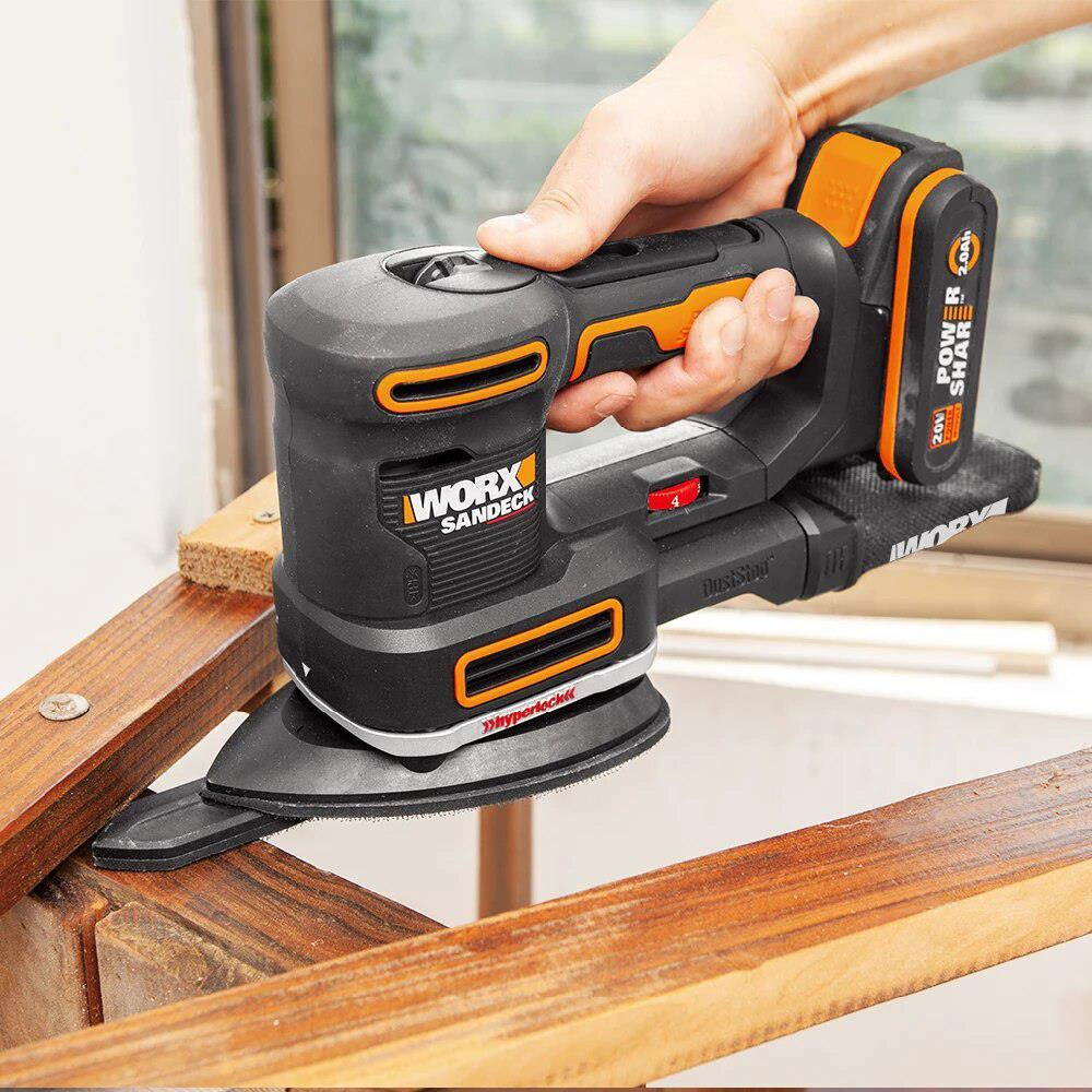 Mano che tiene una levigatrice nera e arancione utilizzata su superfici in legno.