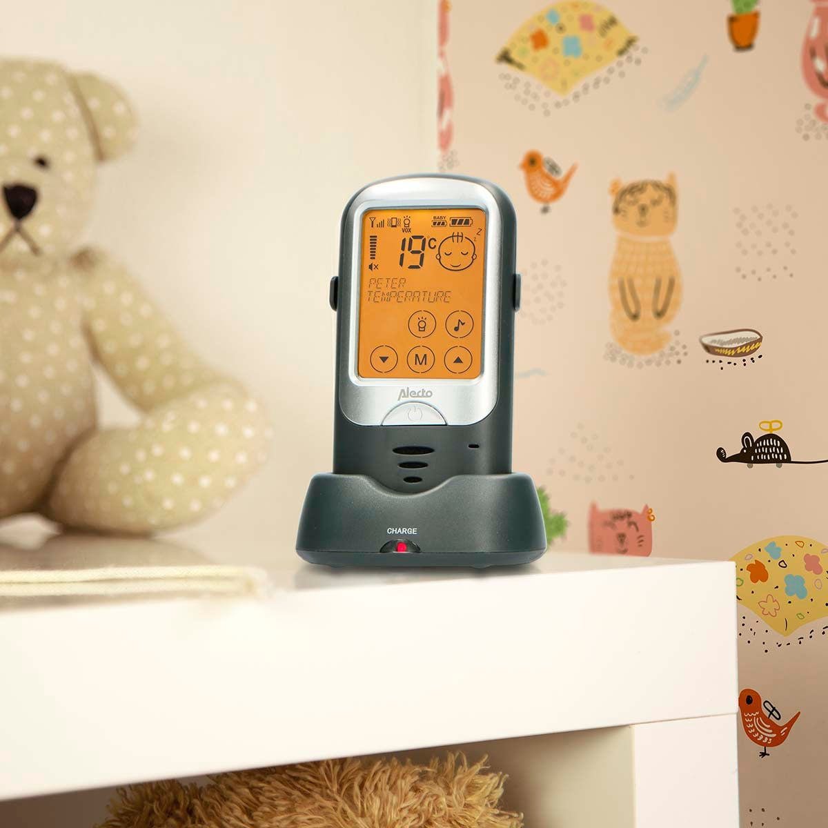 Ein Babyfon-Monitor steht auf einer Ladebasis neben einem Teddybären.