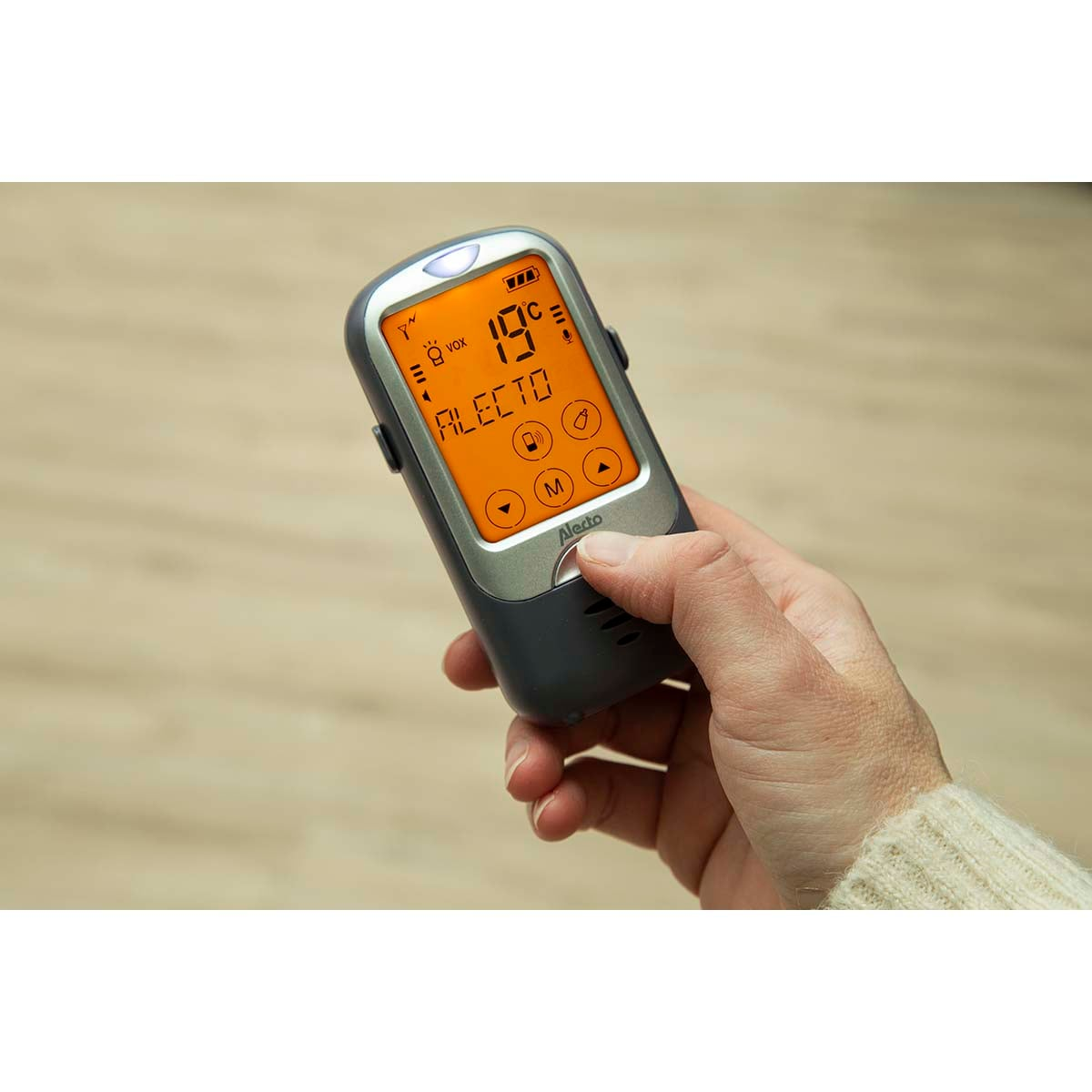 Hand hält einen dunkelgrauen Alecto Baby Monitor mit 19°C und anderen Symbolen.