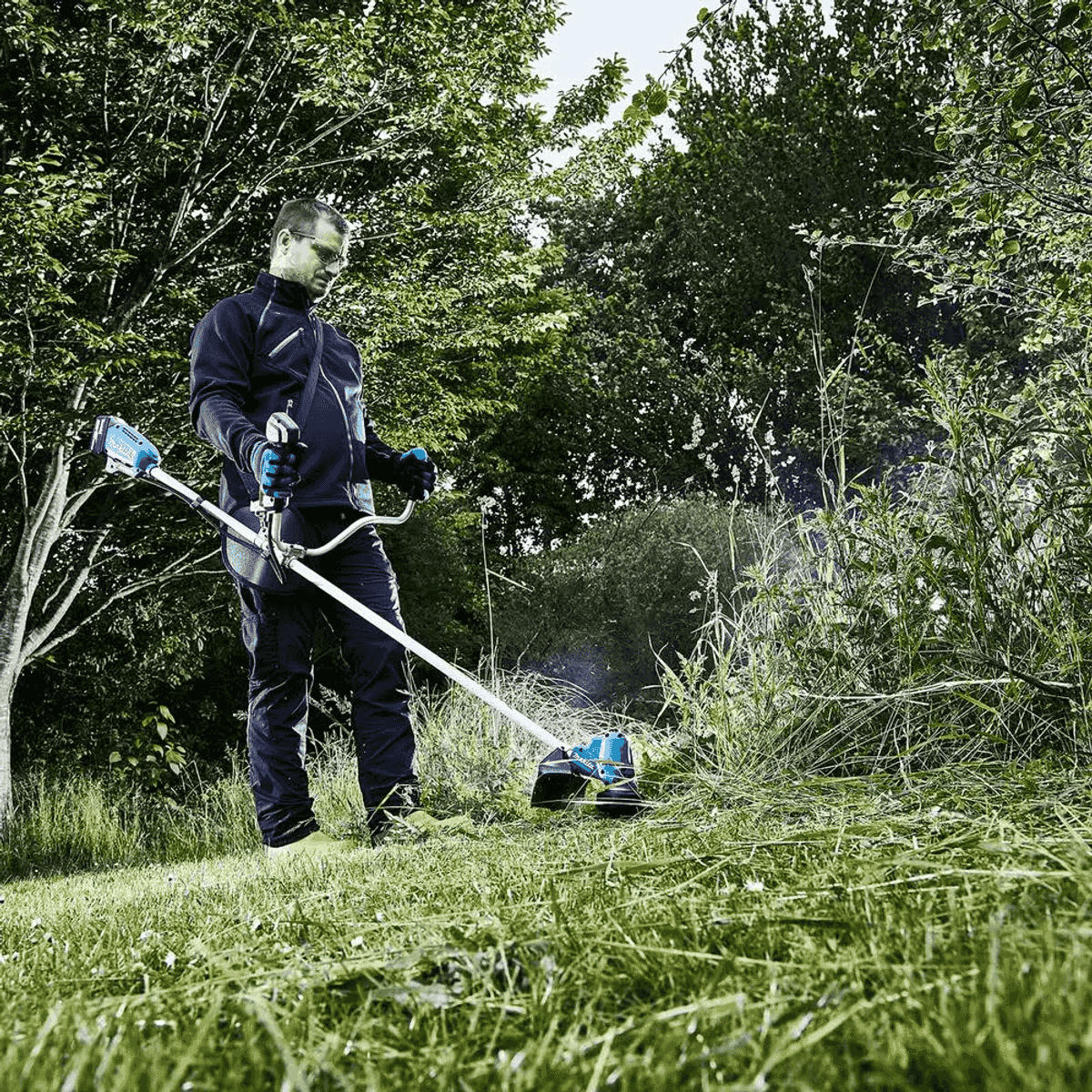 Mann trimmt Gras im Freien mit einem blauen und silbernen Rasentrimmer.