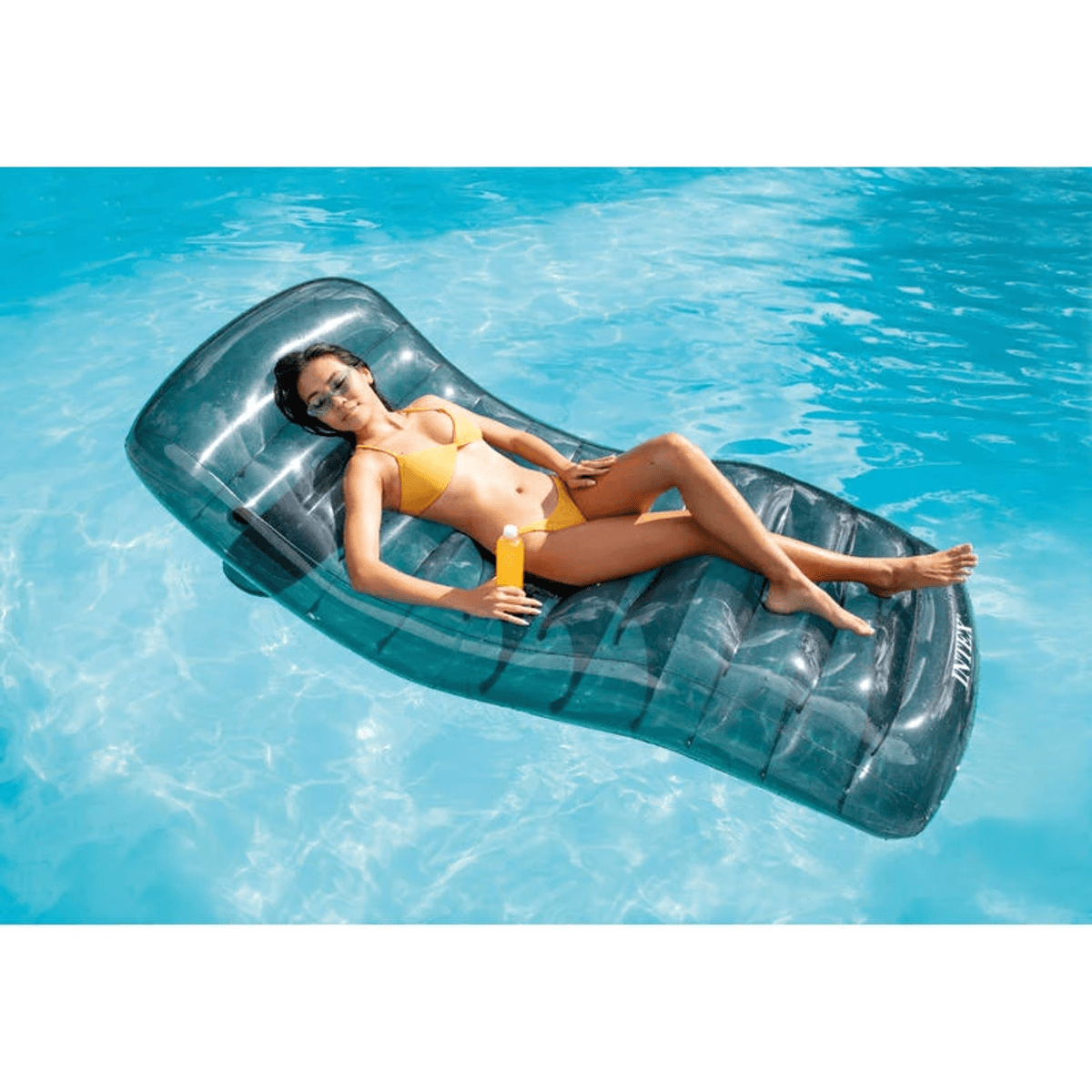Frau in gelbem Bikini auf Luftmatratze im Pool mit Sonnencreme.