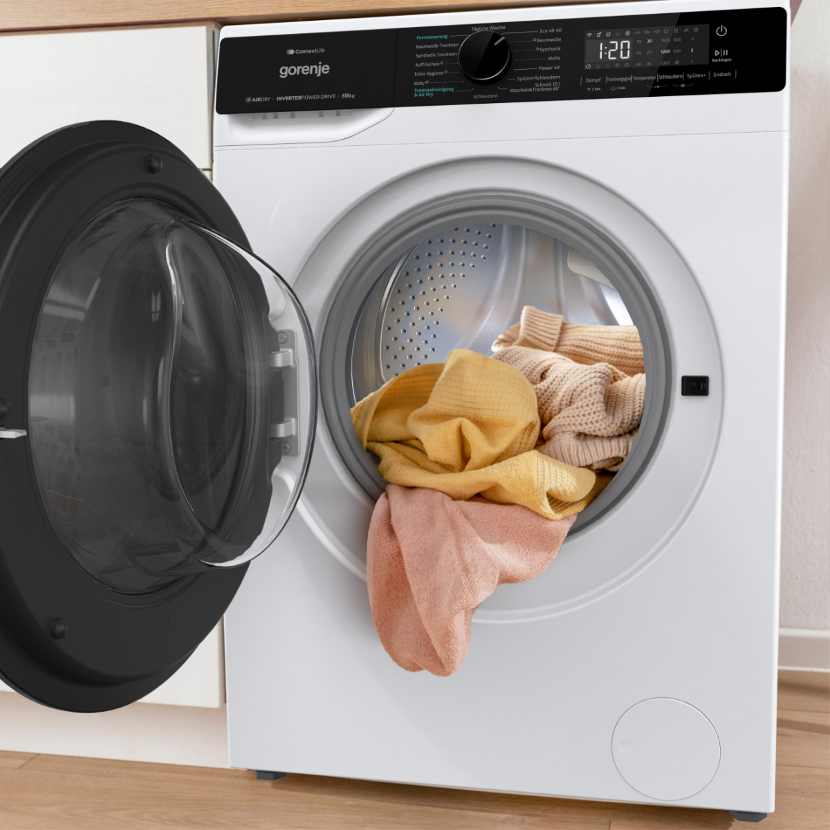 Eine weiße Gorenje Waschmaschine mit geöffneter Tür und bunter Wäsche im Inneren.
