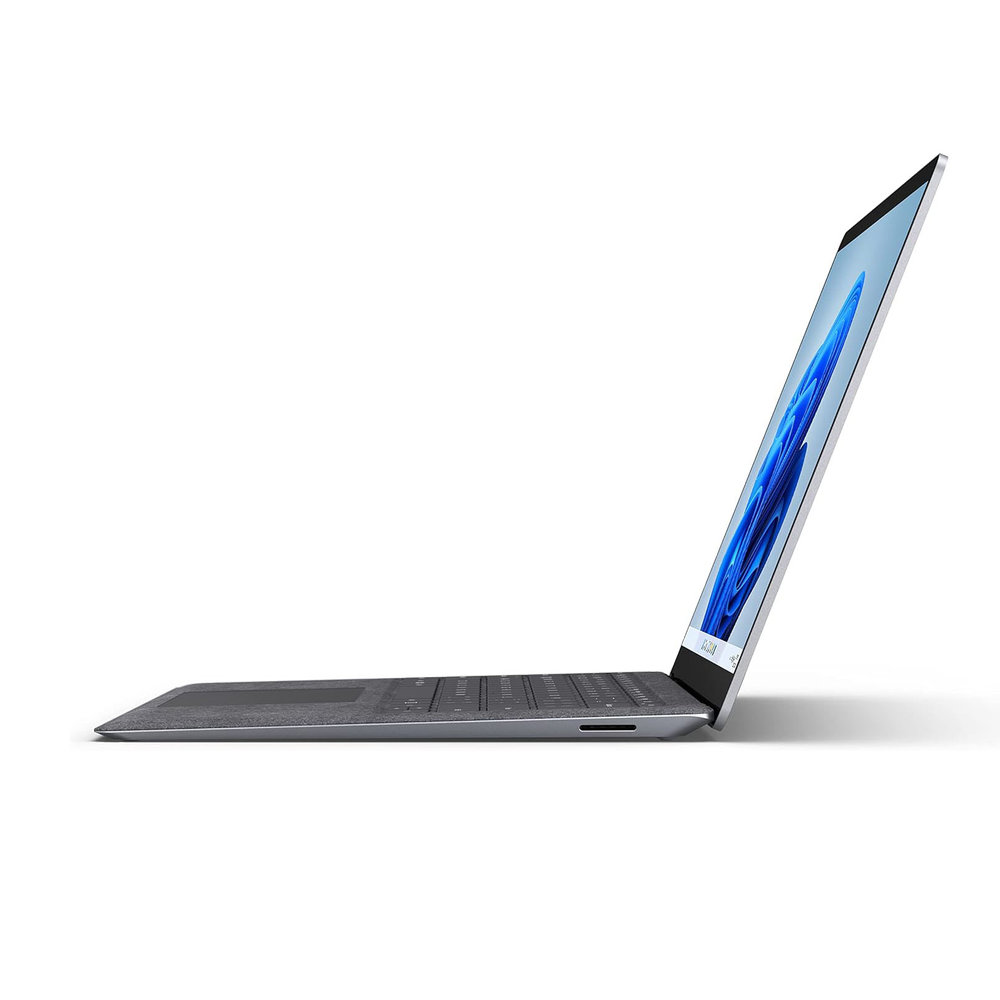 Un ordinateur portable gris vu de profil sur fond blanc.