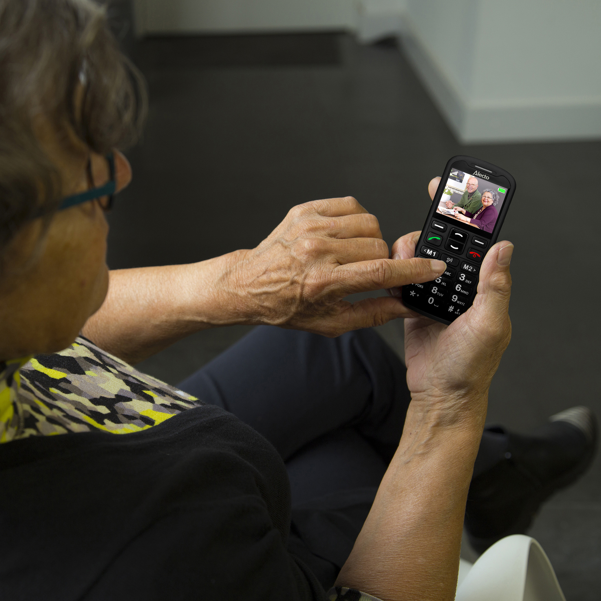 Ältere Frau mit Brille telefoniert mit einem Senioren-Handy mit Videoanruf.