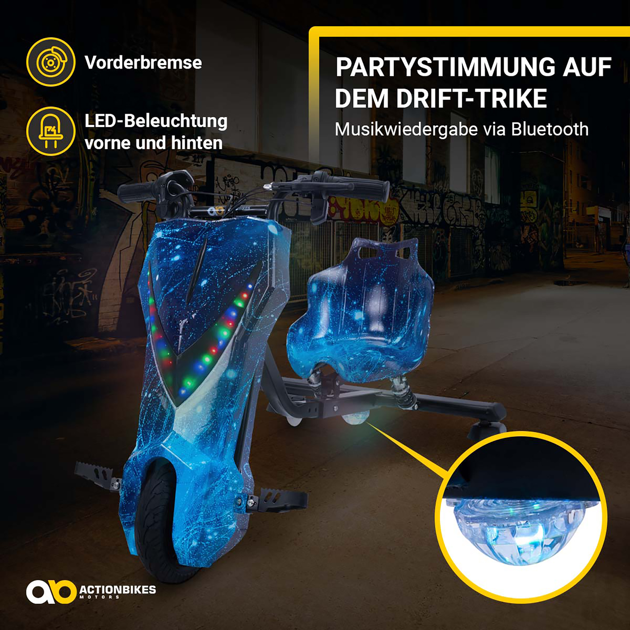 Ein blaues Drift-Trike mit LED-Beleuchtung und Sternenmuster steht nachts vor Graffiti-Wänden.