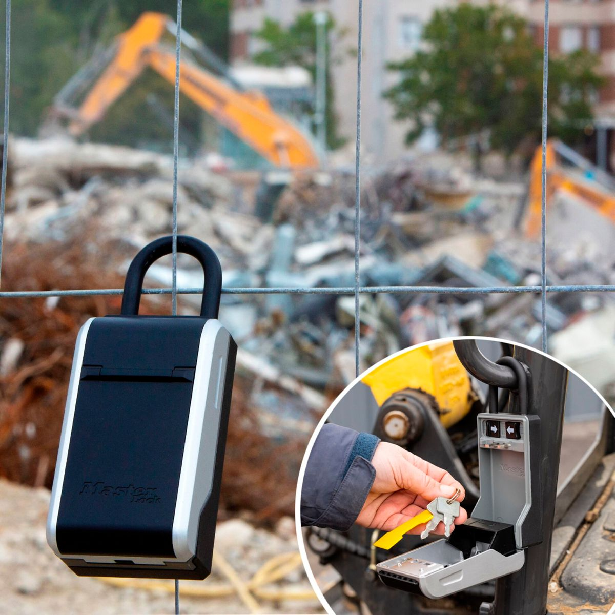 Una cassetta portachiavi Master Lock nera è su una recinzione in un cantiere di demolizione con escavatori.