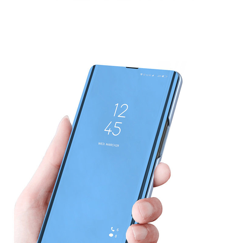 Eine Hand hält ein blaues Klapphandy mit Uhrzeit und Datum auf dem Bildschirm.
