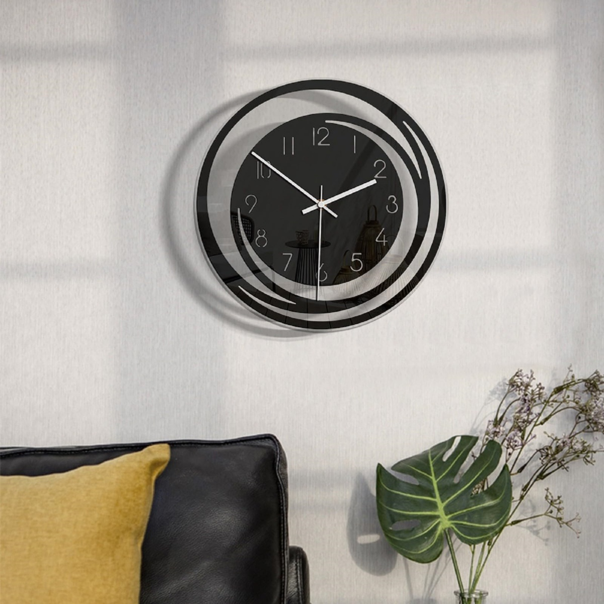 Moderne schwarze Wanduhr mit stilisierten Ringen und weißen Zeigern.