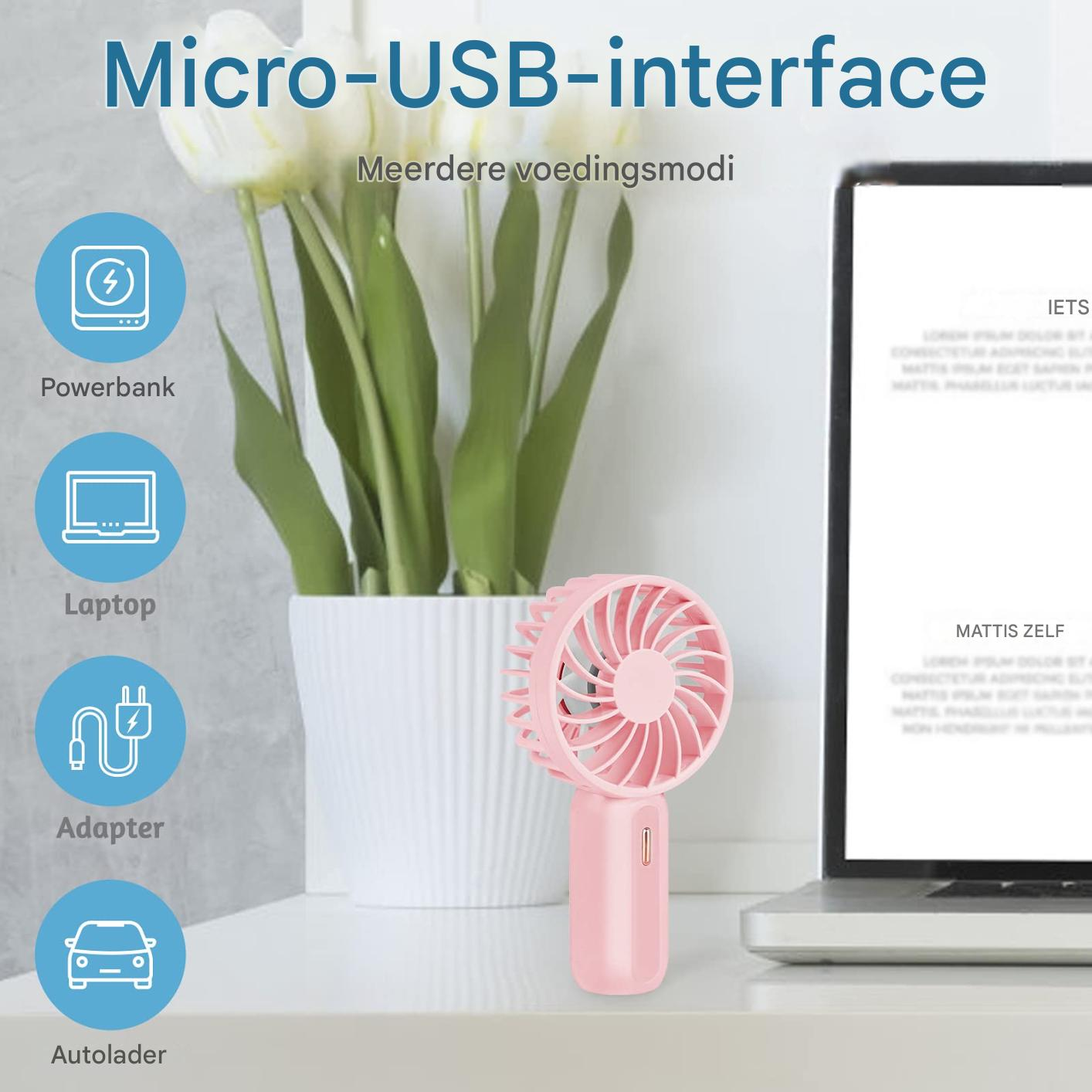 Ein pinker Mini-Ventilator steht neben einem Laptop vor einer Topfpflanze.