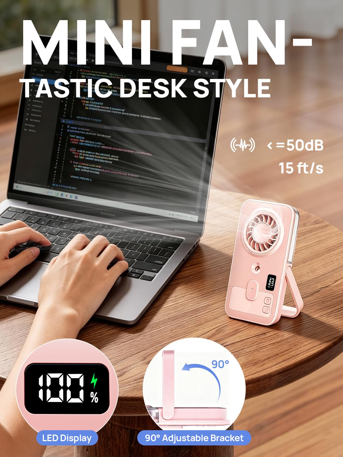 Ein rosafarbener Mini-Ventilator steht auf einem Holztisch neben einem Laptop mit Code.