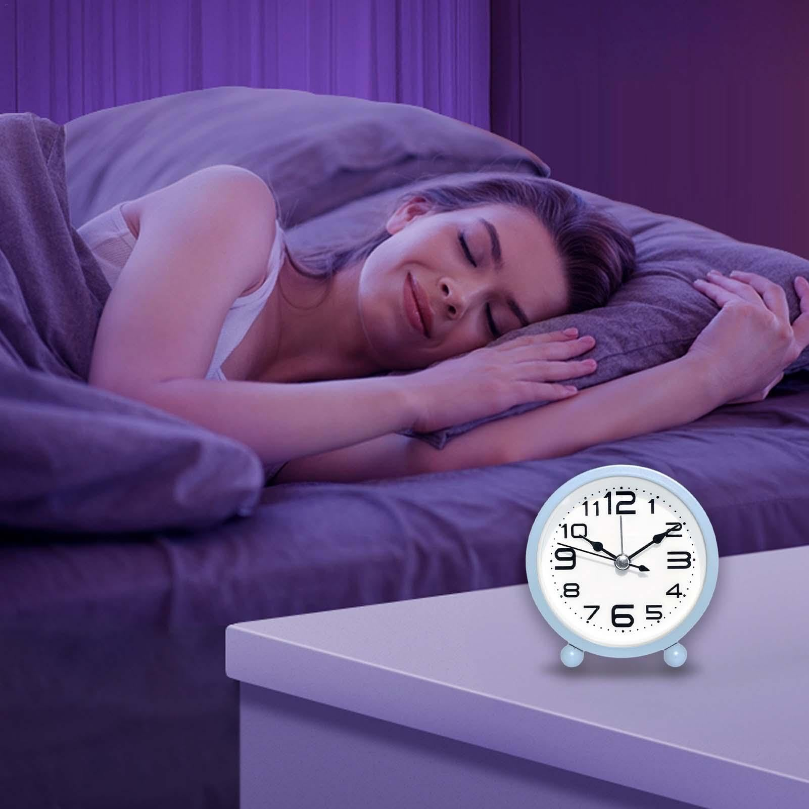 Eine Frau schläft im Bett, ein Wecker steht auf dem Nachttisch.