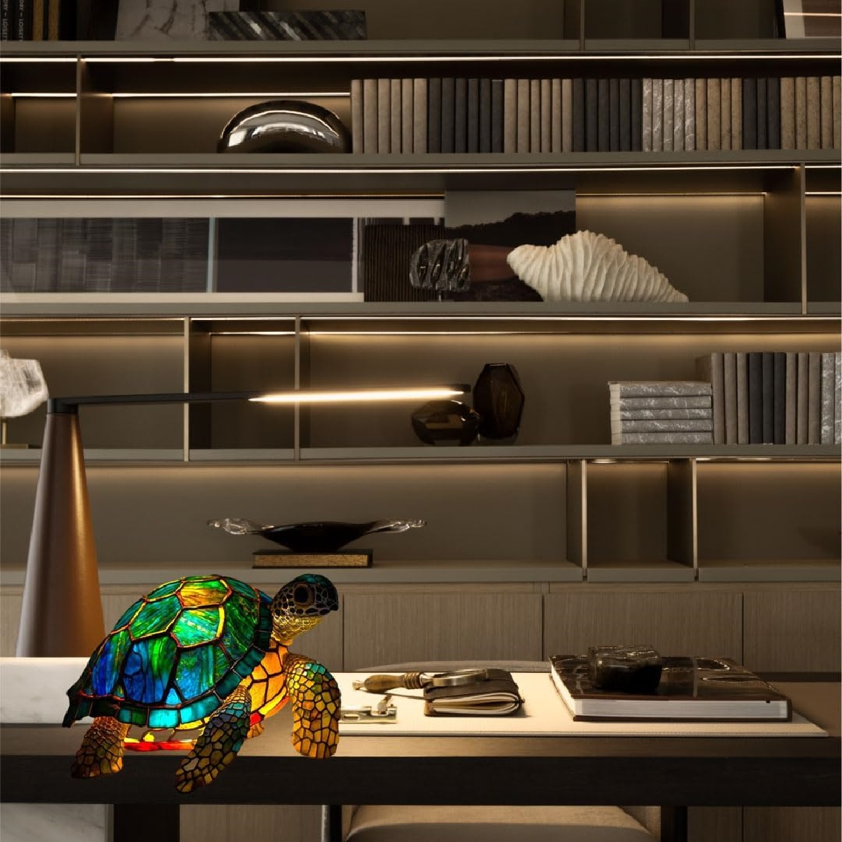 Eine bunte Glas Schildkröte steht auf einem Schreibtisch vor einem Regal voller Bücher.