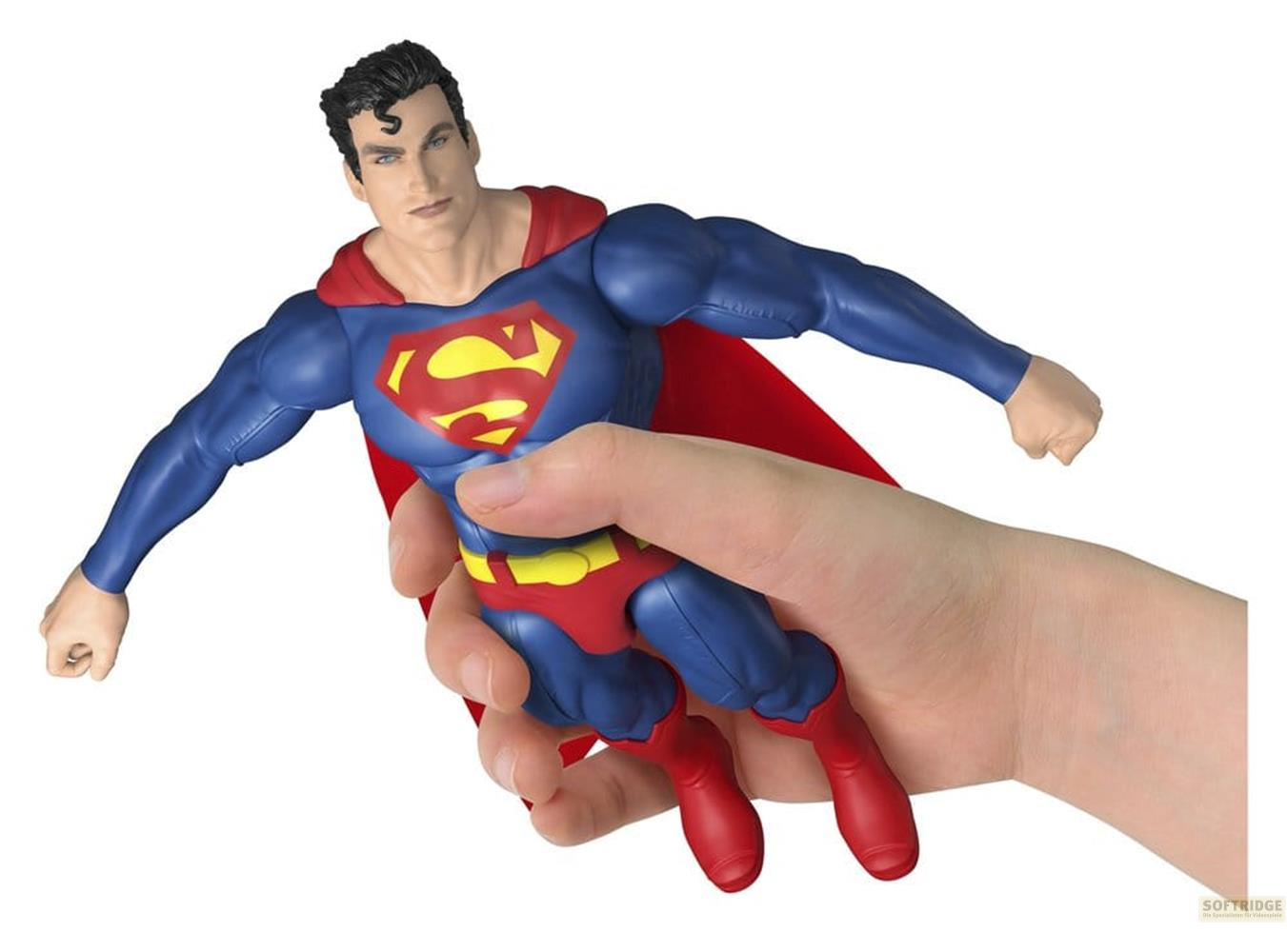 Figura de Superman sostenida por una mano, fondo blanco.