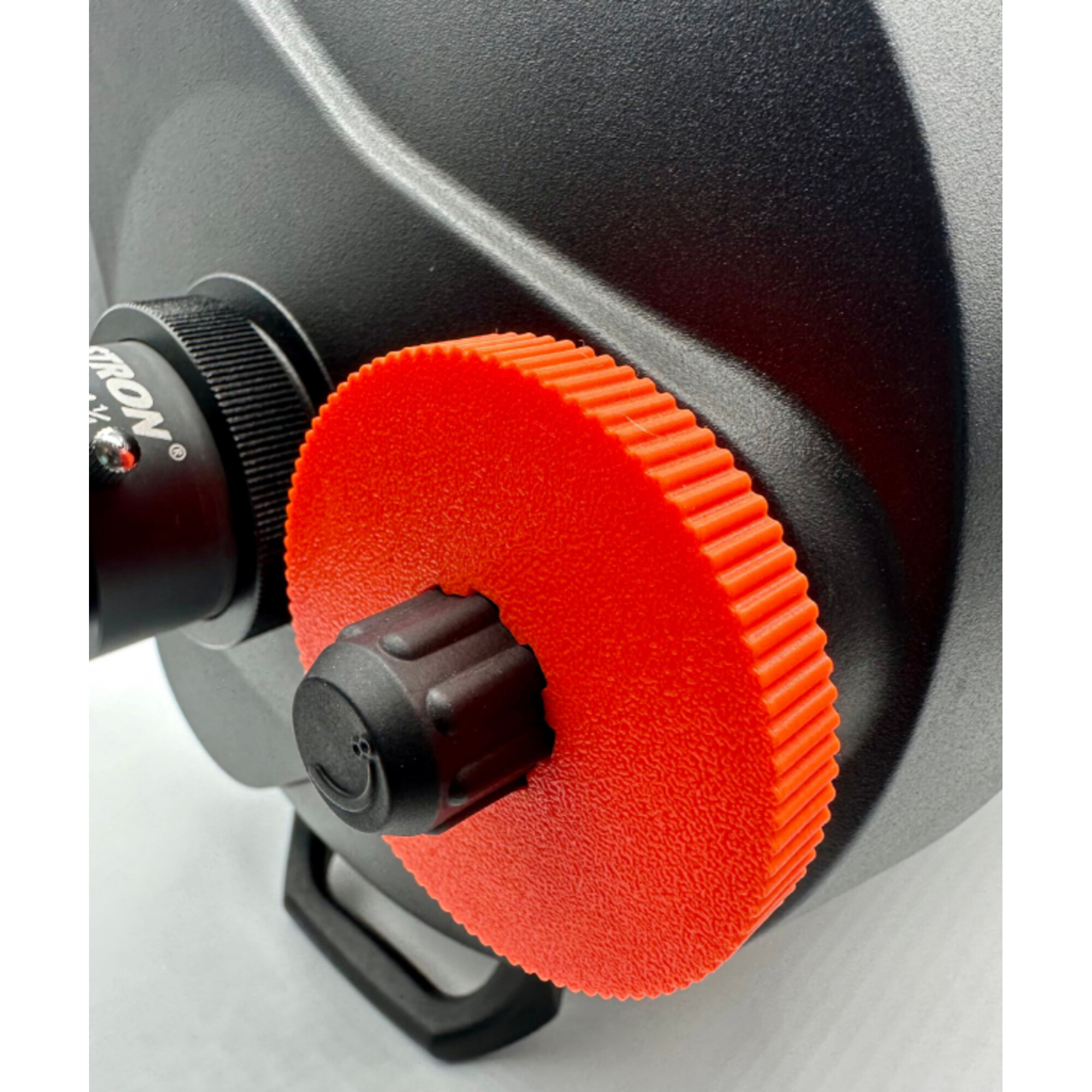 Ein schwarzes Objekt mit einem orangen, gerippten Rad und einem schwarzen Knopf.
