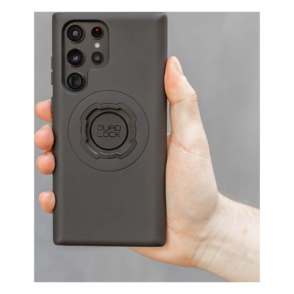 Eine Hand hält ein dunkles Smartphone mit einer Quad Lock Halterung.