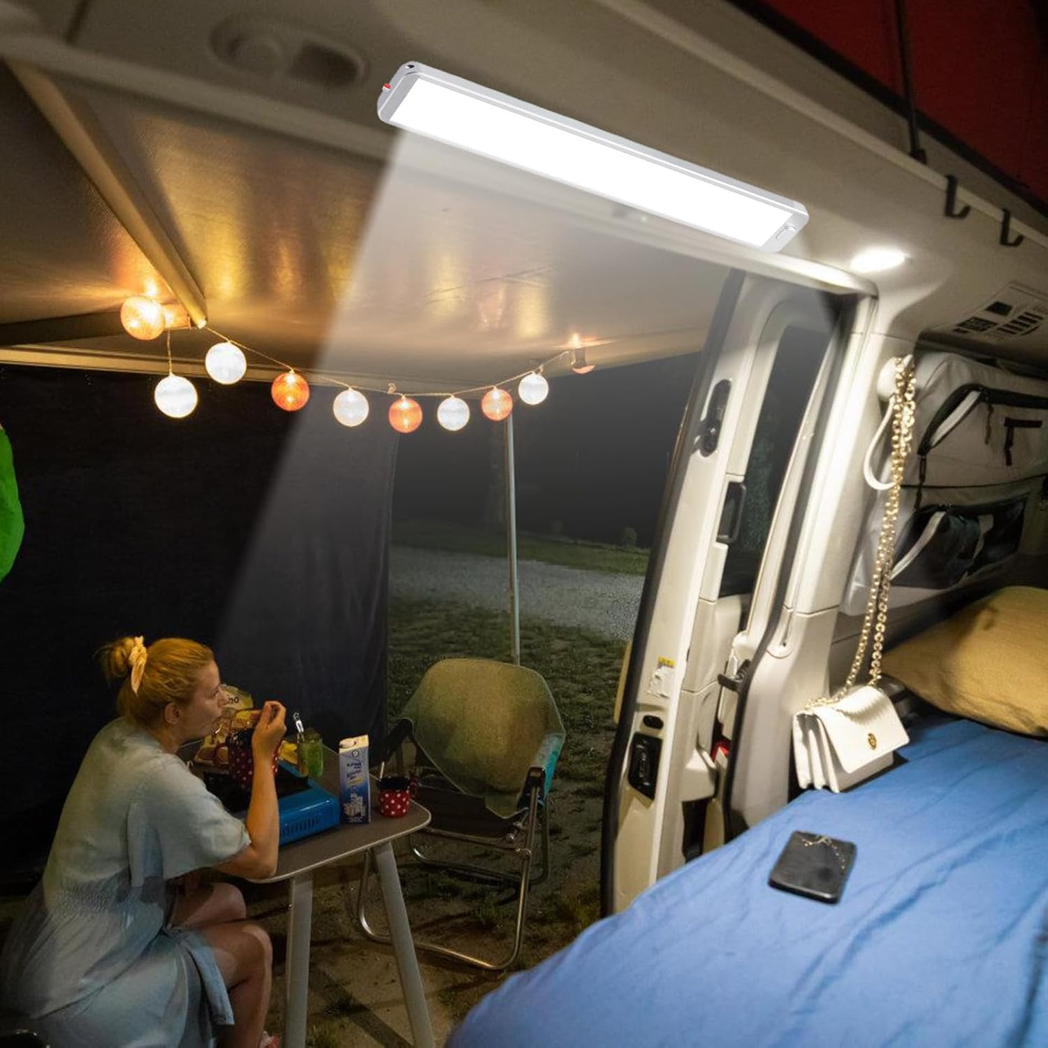 Frau isst im Camper, beleuchtet von LED-Streifen und Lichterketten.
