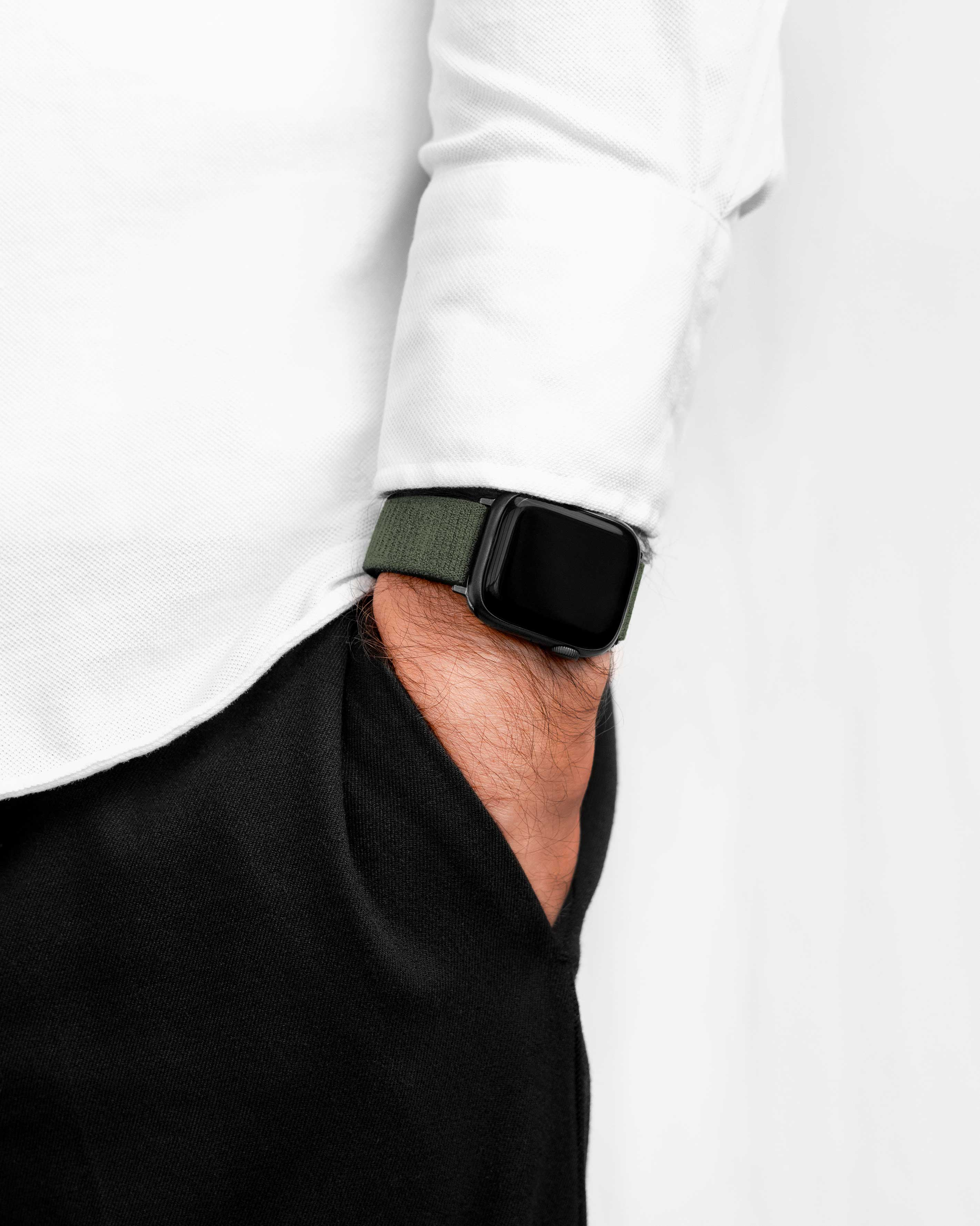 Eine Person in einem weißen Hemd und schwarzer Hose trägt eine grüne Smartwatch.