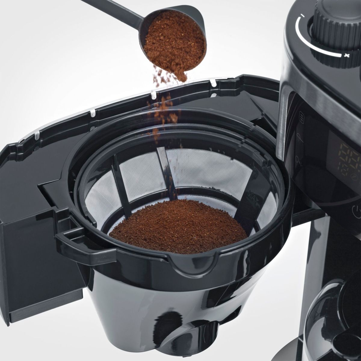Café molido vertiéndose desde una cuchara a un portafiltro.