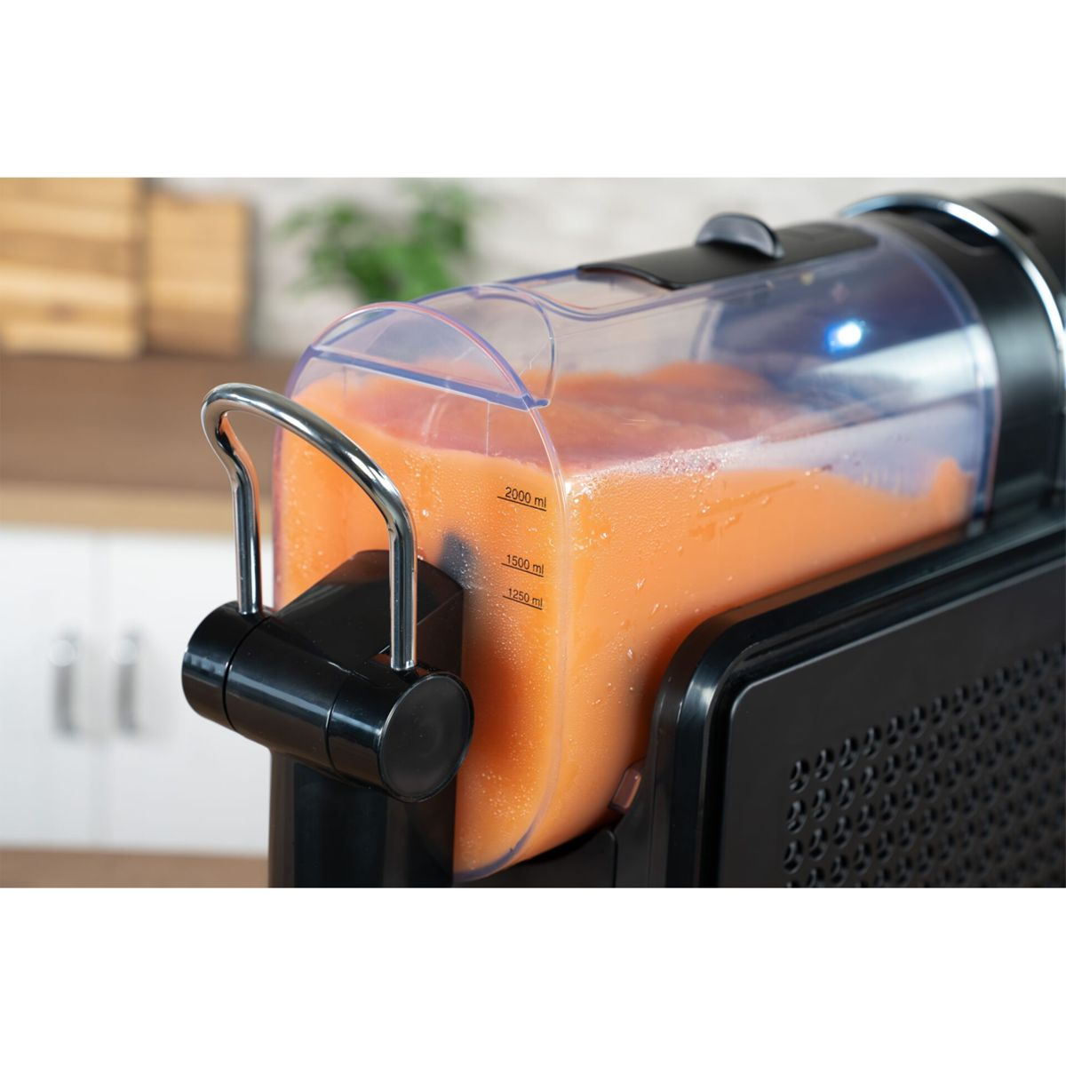 Una centrifuga nera con un contenitore pieno di succo d'arancia.